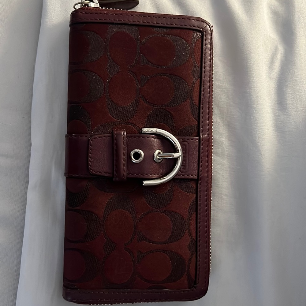 Burgundy Coach zip around wallet with a buckle in the front. Used